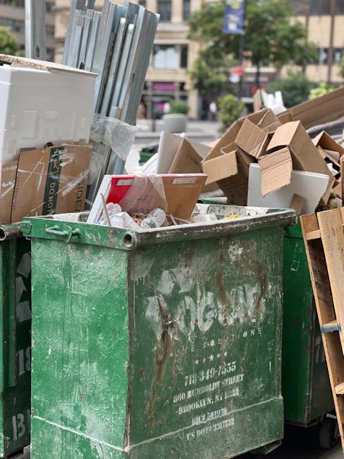 An outdoor scene in a commercial or residential area showing multiple overflowing waste bins and scattered rubbish on the pavement, including cardboard boxes, plastic bags, paper, and packaging materi